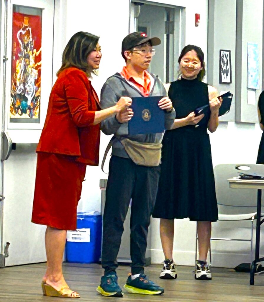 Student recieving a certificate from congress woman Grace Meng.