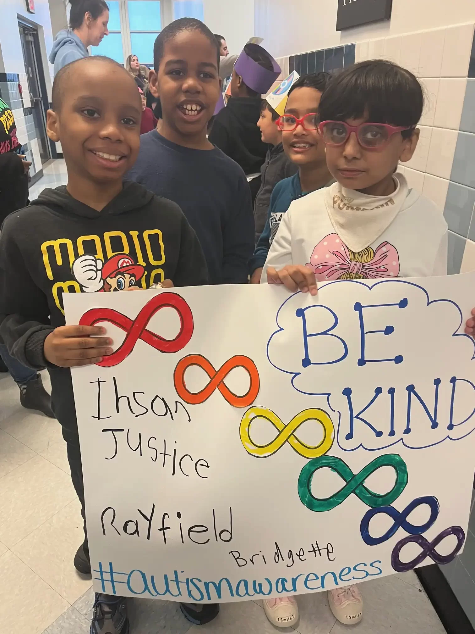 four boys holding a sign with the words "be kind"