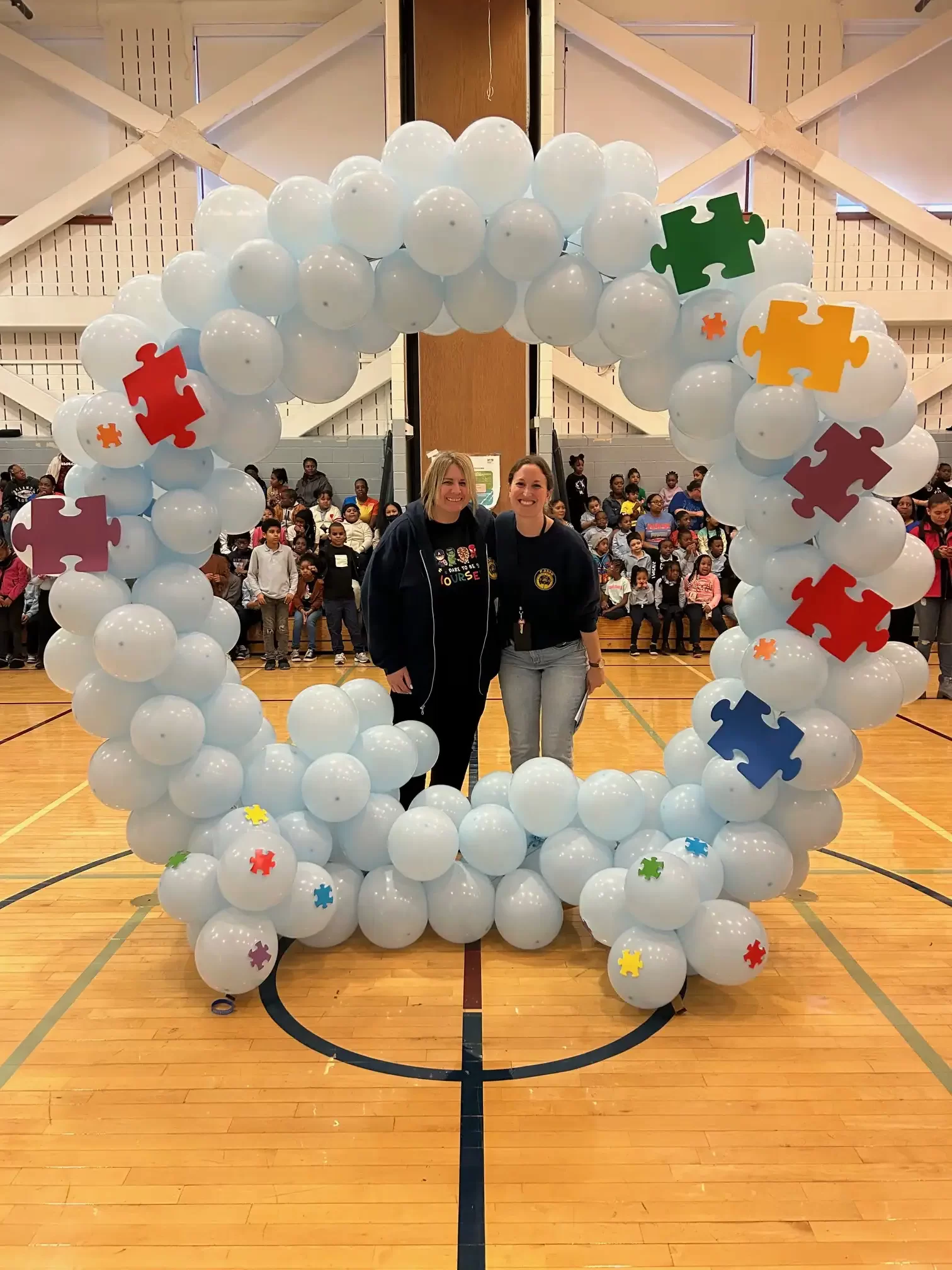 two women under a balloon arch with puzzle pieces