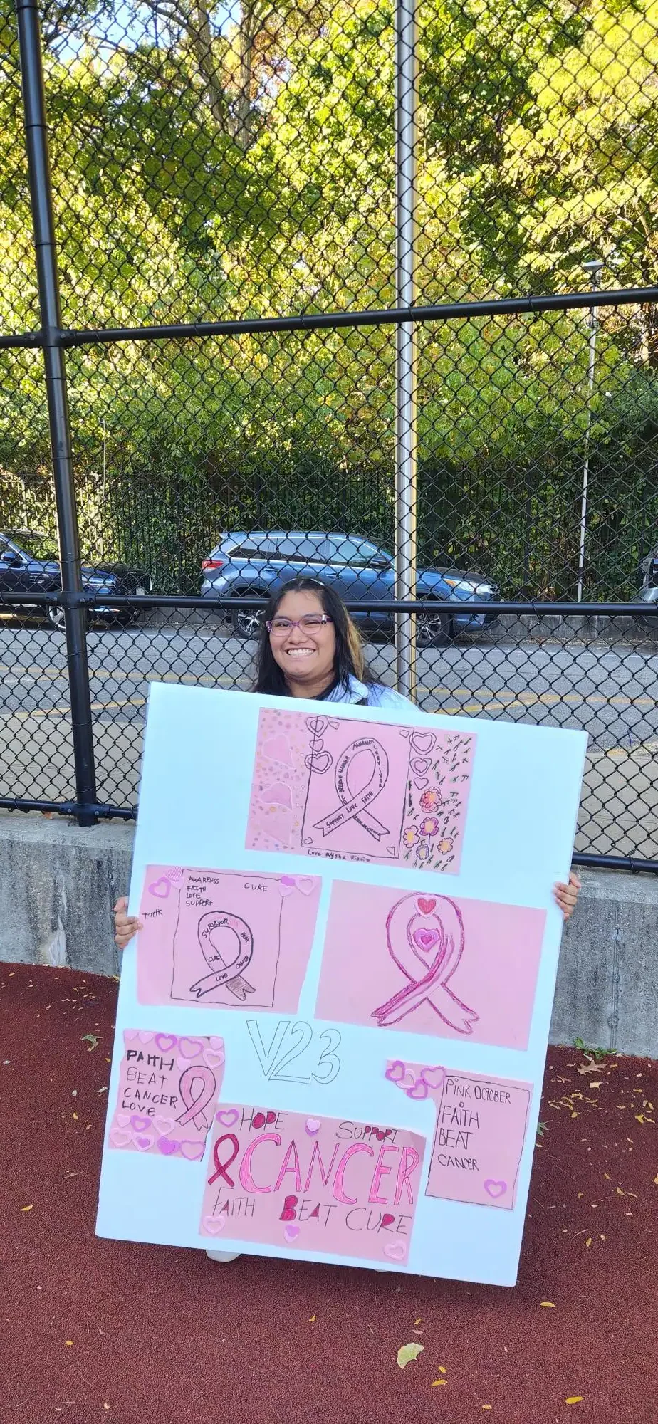 student wearing pink holding a breast cancer fundraiser banner