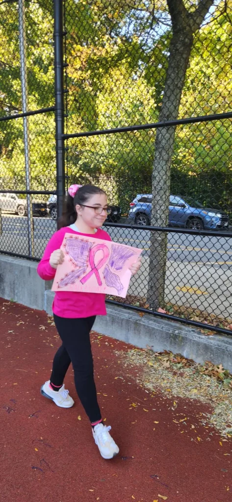 student wearing pink holding a breast cancer fundraiser banner