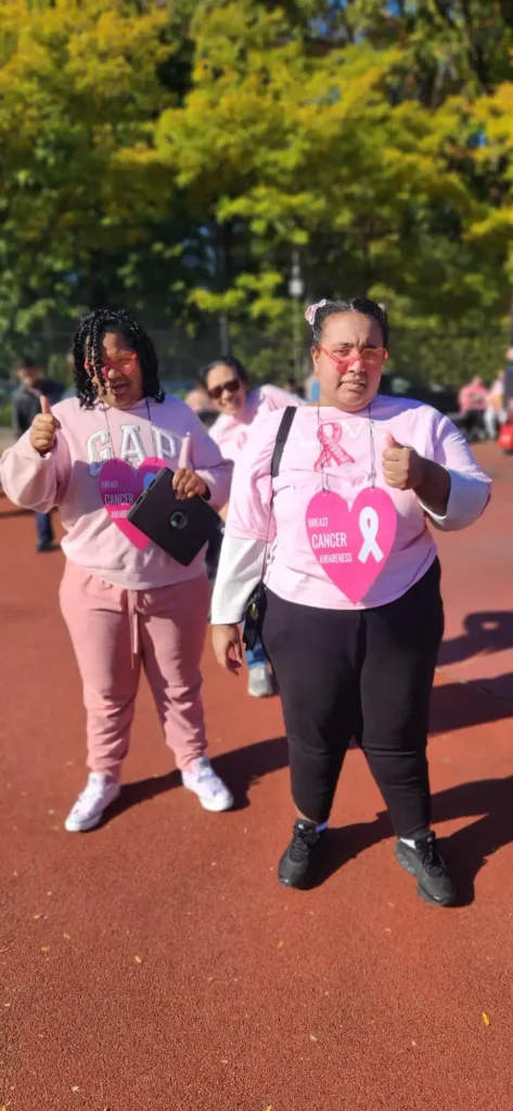 two students wearing pink holding a breast cancer fundraiser banner