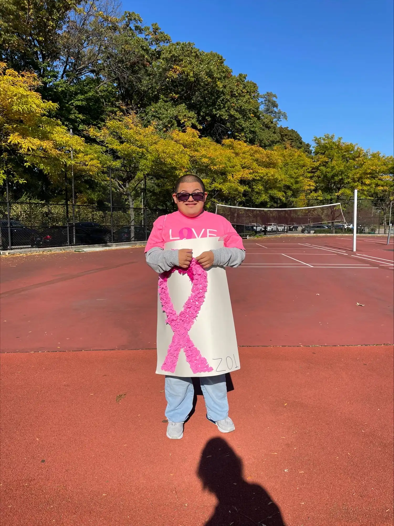 student wearing pink holding a breast cancer fundraiser banner