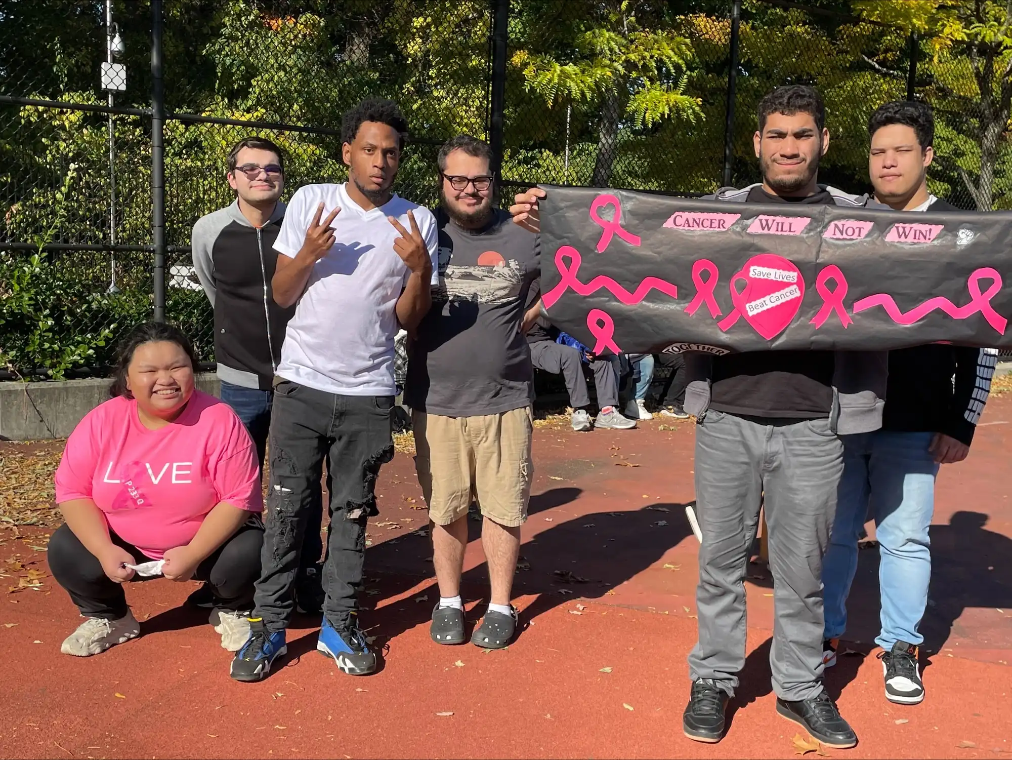 six students wearing pink holding a breast cancer fundraiser banner