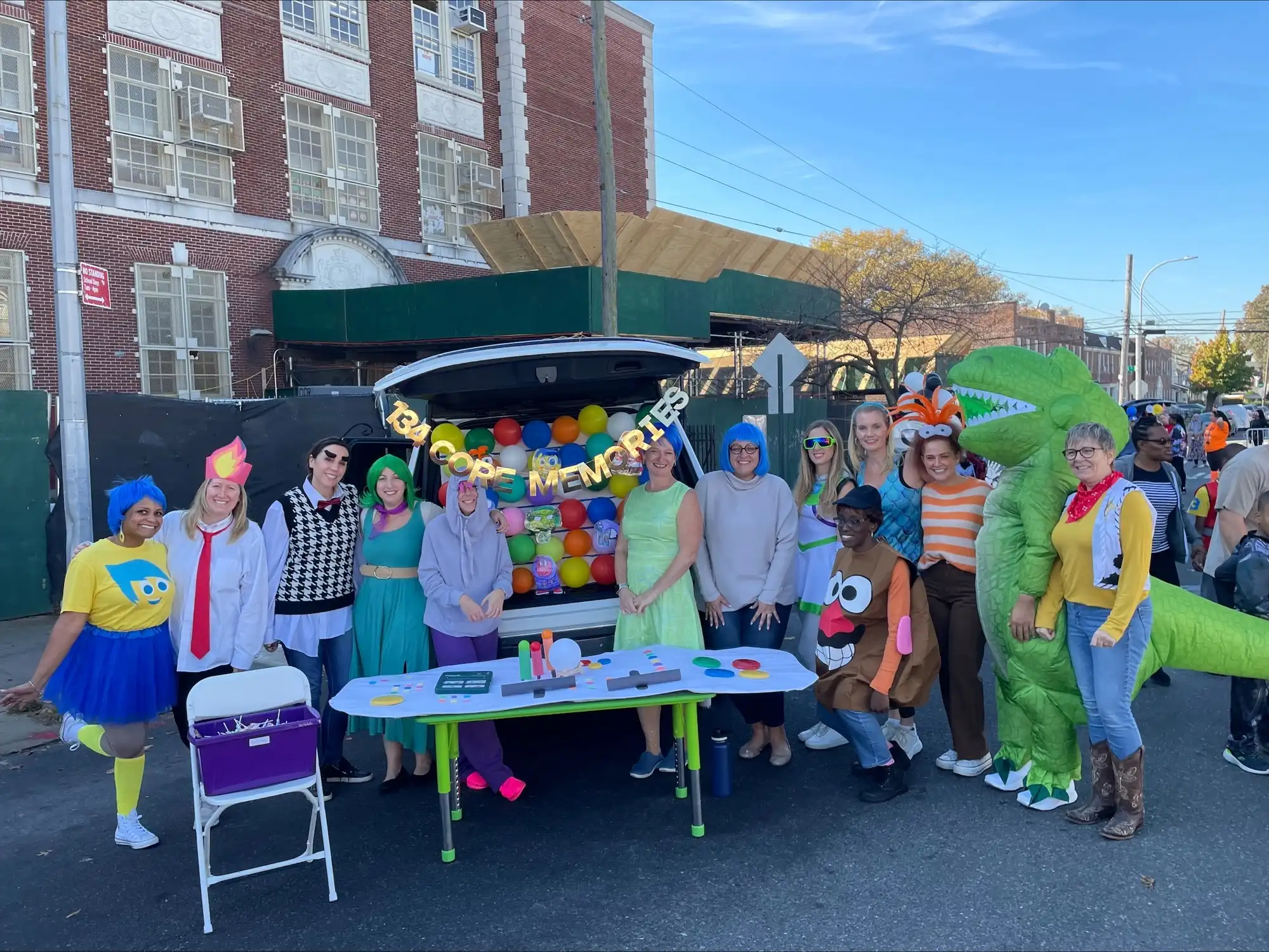 Students and teachers in halloween costumes outside in the school yard.