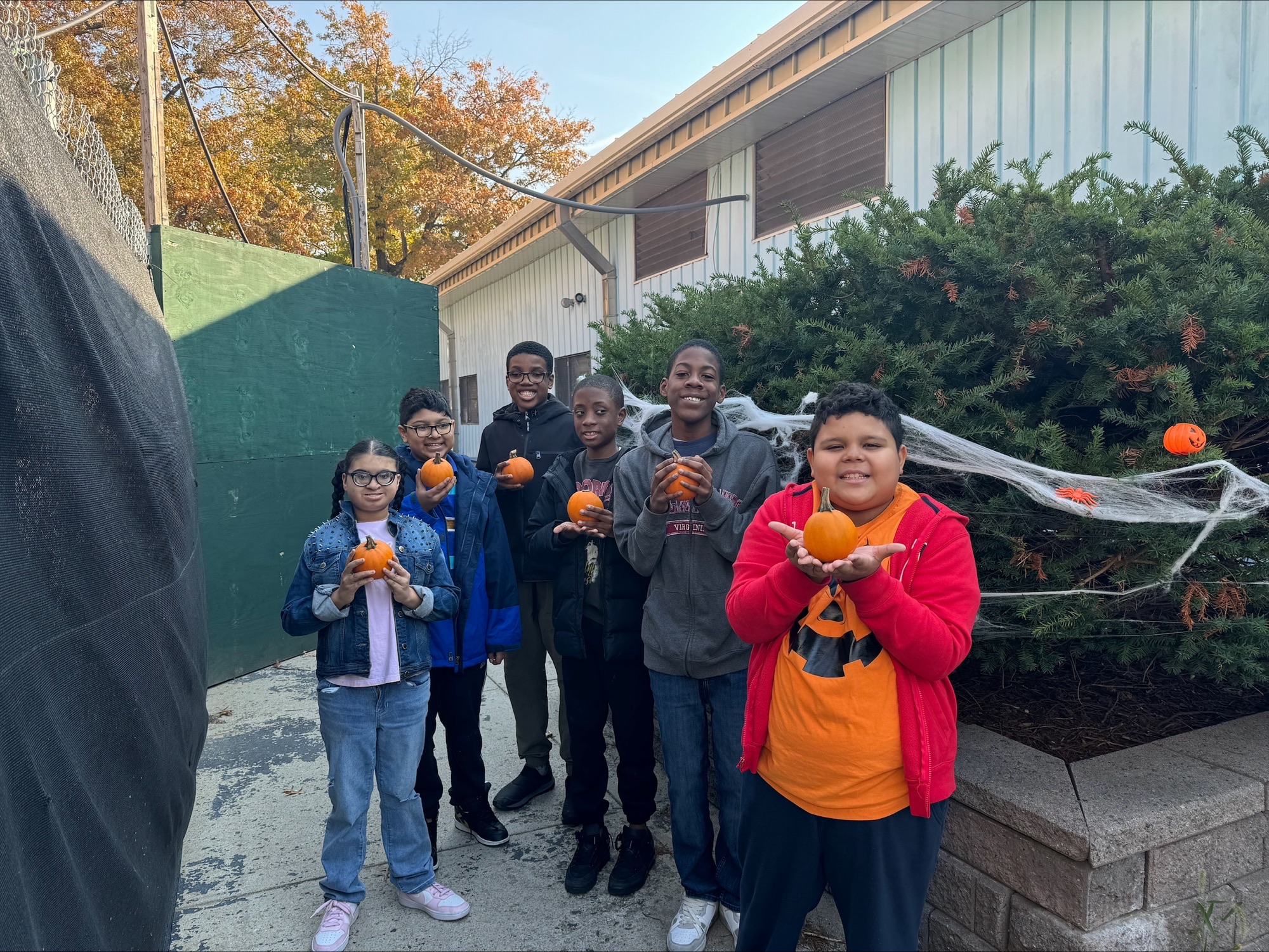 six students outside holding pumpkins