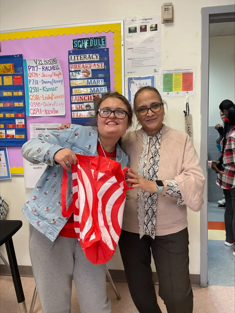 Student holding a shopping bag next to her teacher