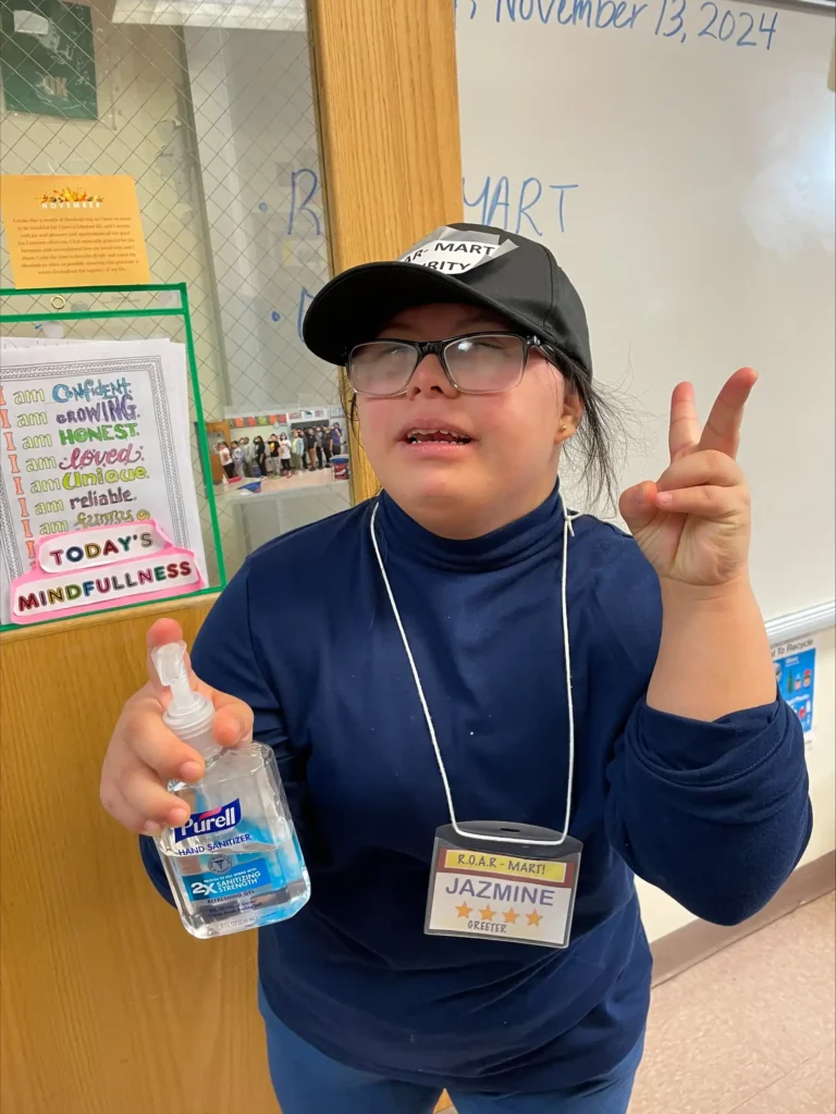 Student holding hand sanitizer in front of her classroom